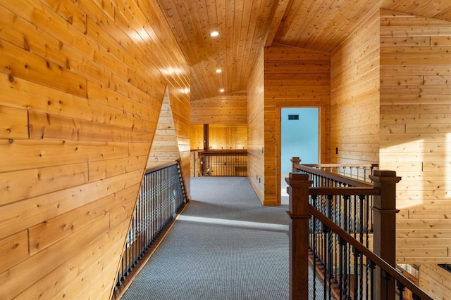 corridor featuring wood ceiling, wooden walls, vaulted ceiling, and an upstairs landing