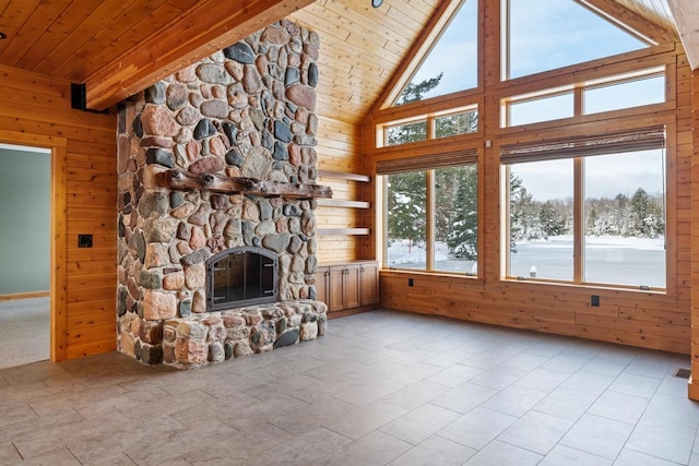 unfurnished living room featuring beamed ceiling, wood walls, a fireplace, and wooden ceiling