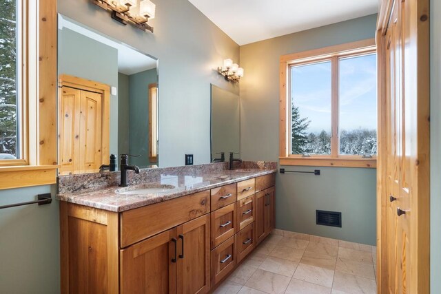 bathroom with visible vents, a sink, baseboards, and double vanity