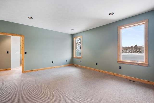 carpeted spare room featuring baseboards, recessed lighting, visible vents, and a healthy amount of sunlight