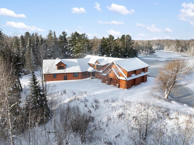 snowy aerial view featuring a forest view