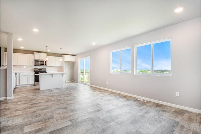 unfurnished living room featuring light wood-style flooring, baseboards, and recessed lighting