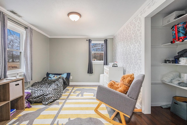 bedroom with baseboards, crown molding, visible vents, and wood finished floors