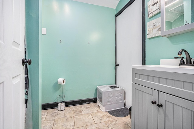 bathroom featuring stone finish flooring, vanity, and baseboards