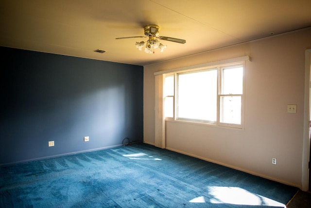 carpeted spare room featuring baseboards, visible vents, and a ceiling fan