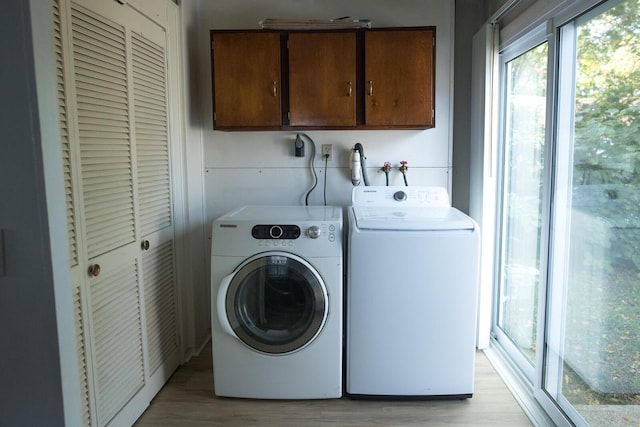 washroom featuring light wood-type flooring, cabinet space, and washer and clothes dryer