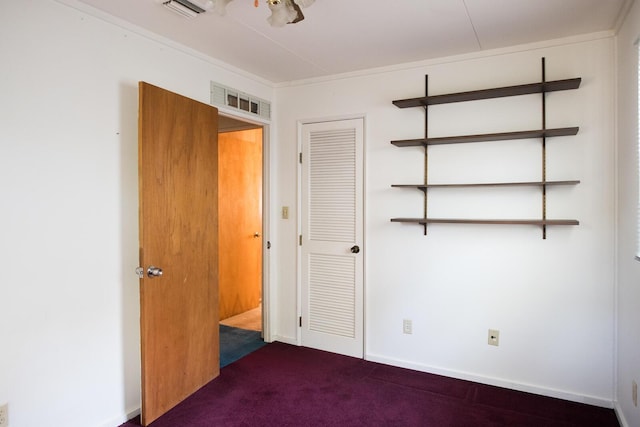 unfurnished room featuring dark colored carpet, visible vents, and baseboards