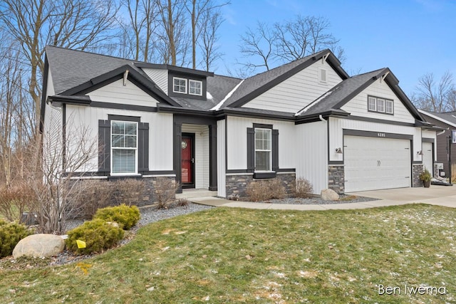 view of front of home with stone siding, a front lawn, a shingled roof, and driveway