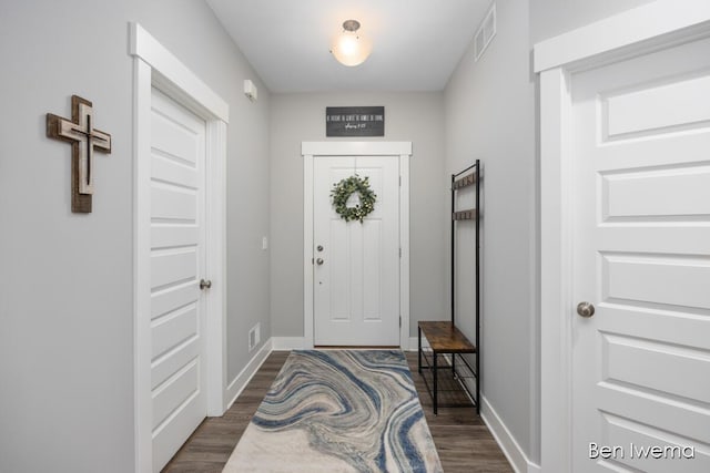 foyer entrance with dark wood-style floors, visible vents, and baseboards