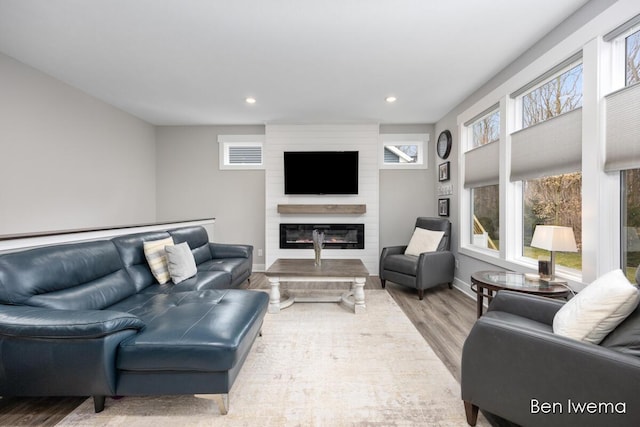 living area featuring baseboards, a fireplace, wood finished floors, and recessed lighting