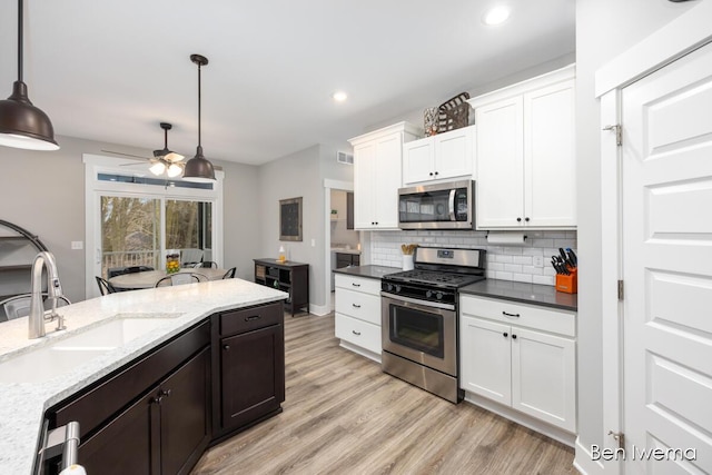 kitchen with stainless steel appliances, tasteful backsplash, visible vents, white cabinets, and a sink