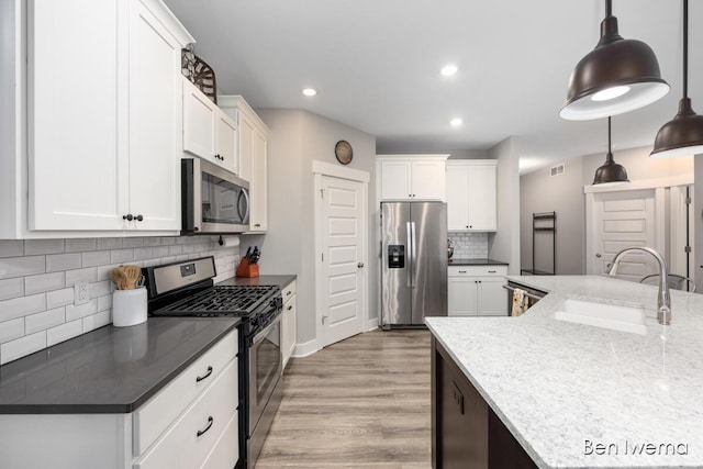 kitchen featuring light wood finished floors, stainless steel appliances, recessed lighting, white cabinets, and a sink