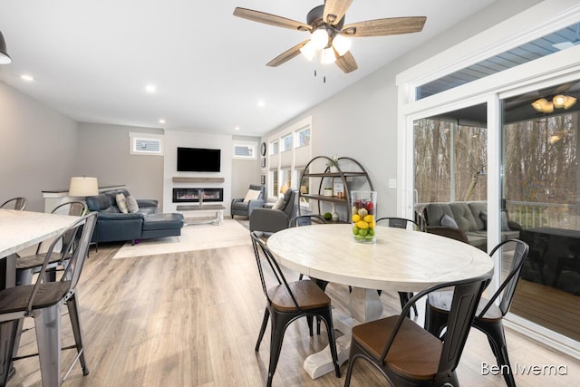 dining room featuring a glass covered fireplace, light wood-style flooring, and recessed lighting