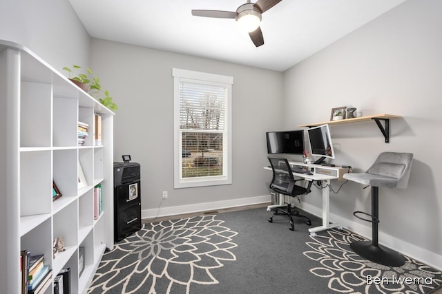 carpeted office with ceiling fan and baseboards