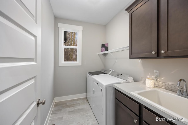 clothes washing area featuring washer and clothes dryer, a sink, cabinet space, and baseboards