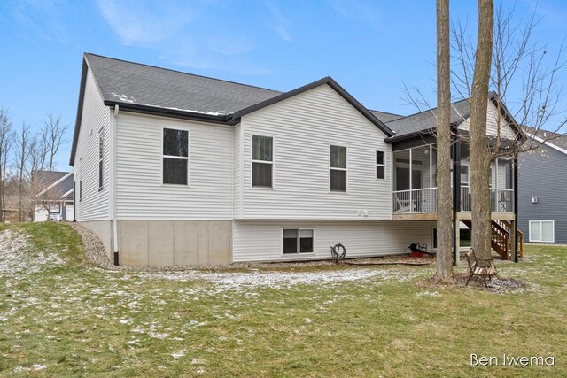 rear view of house with a sunroom, stairway, and a lawn