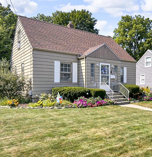 view of front of property with a shingled roof, a front yard, and a chimney