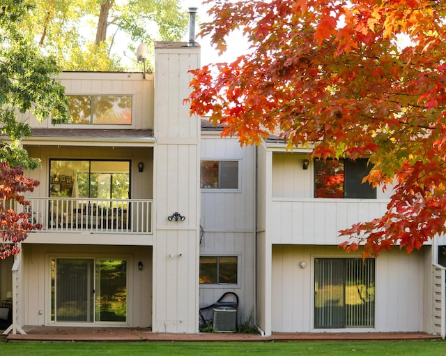 back of house with a chimney and a balcony