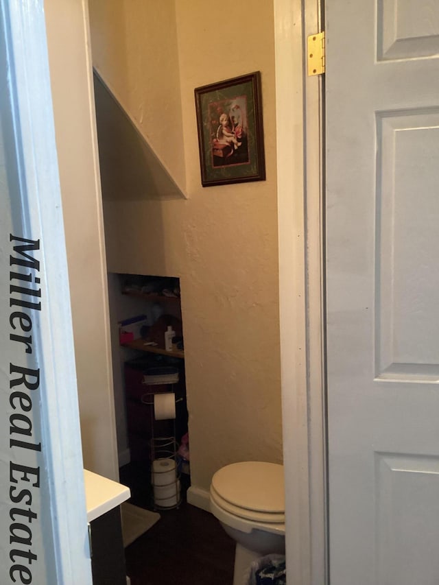 bathroom featuring a textured wall, vanity, and toilet