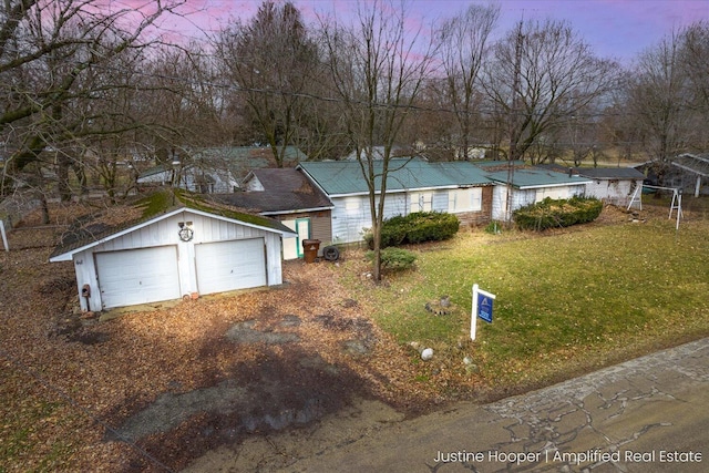 exterior space featuring a garage, a lawn, and an outbuilding