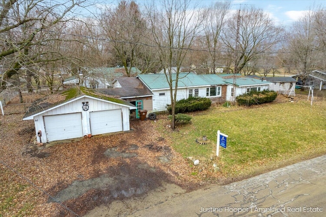 single story home with a front yard, a detached garage, and an outdoor structure