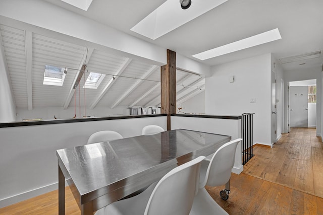 dining area with lofted ceiling, wood-type flooring, and baseboards