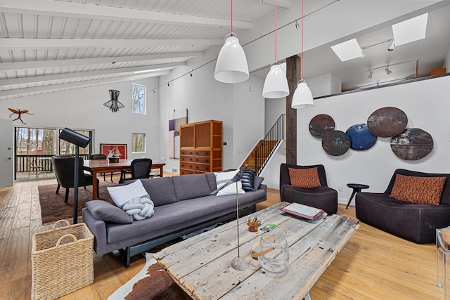 living room with rail lighting, wood-type flooring, high vaulted ceiling, and beam ceiling