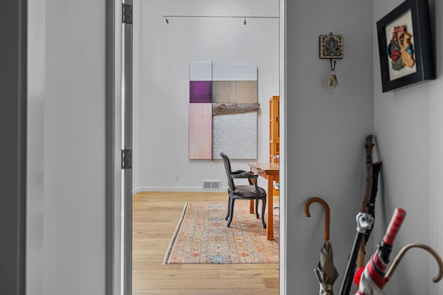 corridor with visible vents, baseboards, and wood finished floors