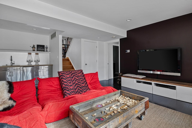 living area with stairway, visible vents, and wood finished floors