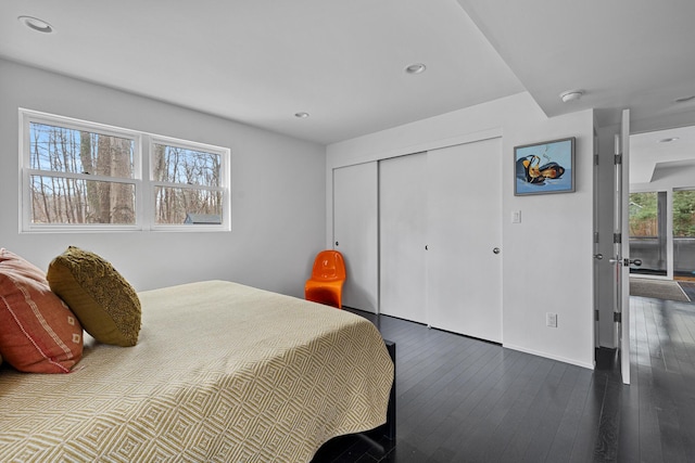 bedroom with a closet, recessed lighting, wood-type flooring, and baseboards