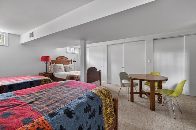 carpeted bedroom with visible vents and two closets