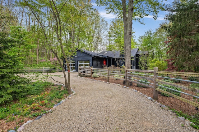 view of front of house featuring an attached garage, a fenced front yard, and gravel driveway