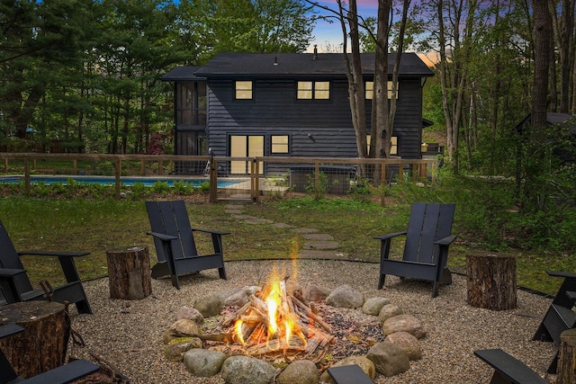 back of property at dusk with an outdoor fire pit and an outdoor pool