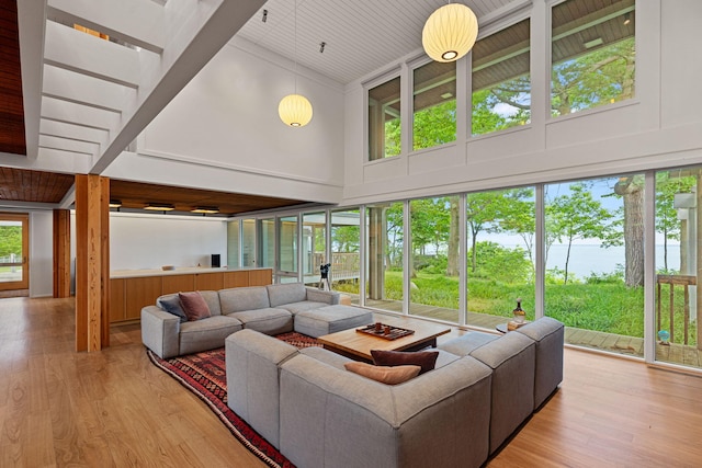 living area with a water view, plenty of natural light, high vaulted ceiling, and wood finished floors