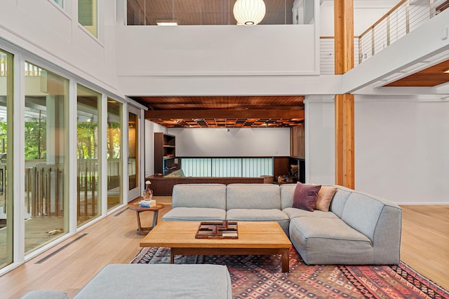 living area featuring a towering ceiling, wood finished floors, and beamed ceiling