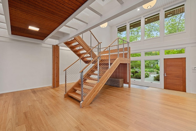 staircase with wooden ceiling, baseboards, a high ceiling, and wood finished floors