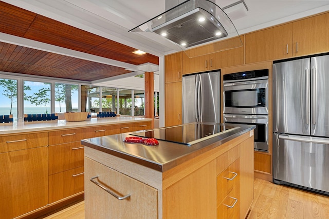 kitchen featuring modern cabinets, appliances with stainless steel finishes, a center island, extractor fan, and light wood-style floors