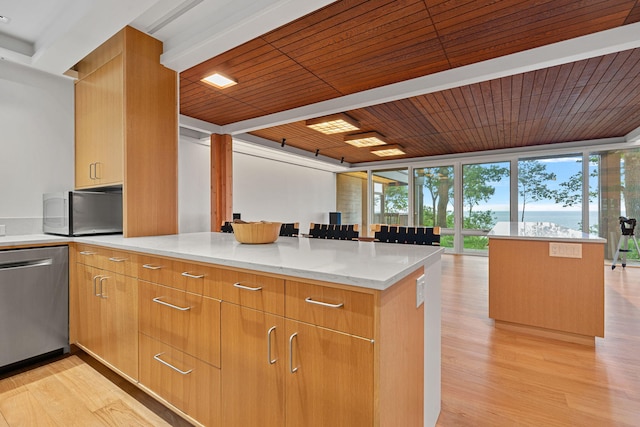 kitchen with stainless steel appliances, light stone counters, a peninsula, and light wood finished floors