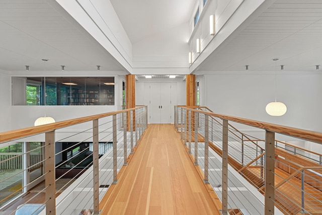 hallway featuring vaulted ceiling, wood-type flooring, and an upstairs landing