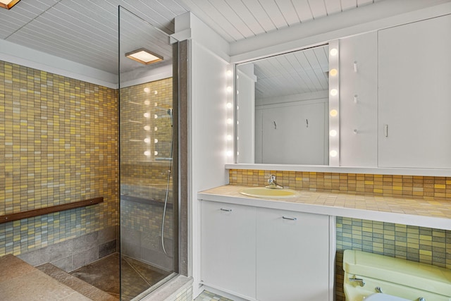 full bath with a tile shower, backsplash, and vanity