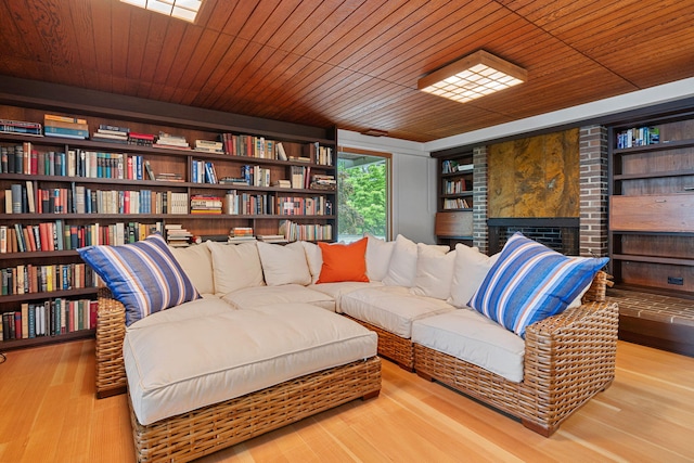 living area featuring built in shelves, wood ceiling, a fireplace, and wood finished floors