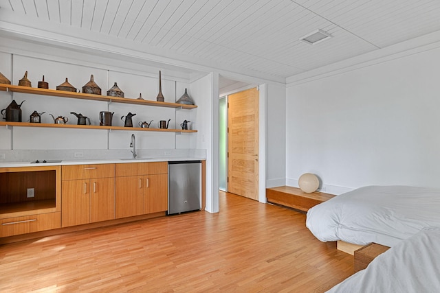 bar with light wood-style flooring, wet bar, a sink, and refrigerator