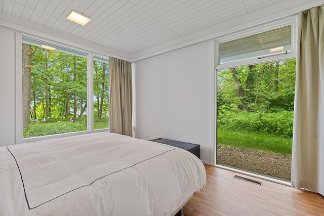 bedroom with access to outside, visible vents, and wood finished floors