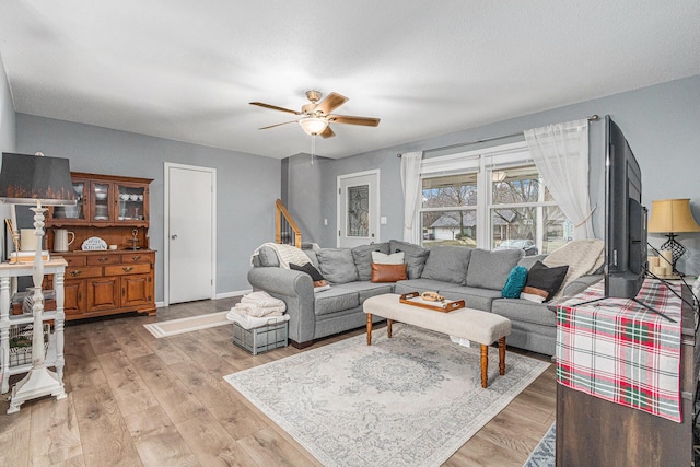 living area with light wood-style flooring, baseboards, and ceiling fan