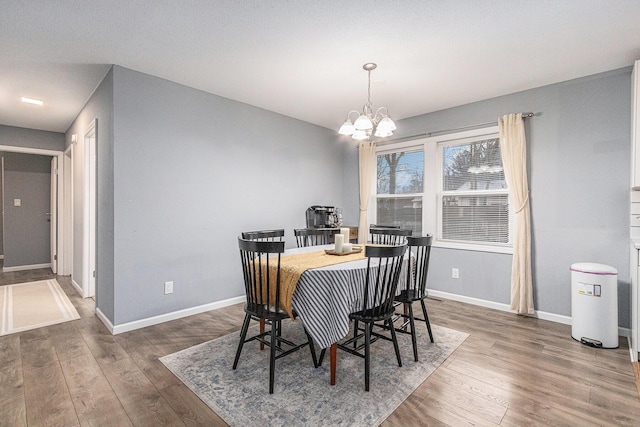 dining room featuring baseboards, a chandelier, and wood finished floors