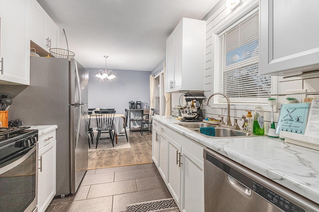 kitchen featuring stainless steel appliances, light countertops, white cabinets, a sink, and a chandelier