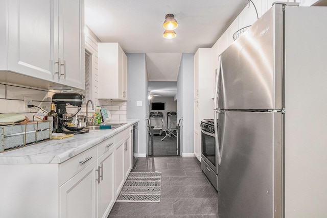 kitchen featuring appliances with stainless steel finishes, white cabinets, backsplash, and light countertops