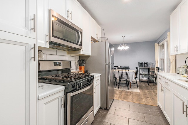 kitchen featuring stainless steel appliances, light countertops, and white cabinets