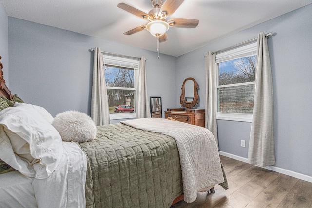 bedroom featuring ceiling fan, baseboards, and wood finished floors