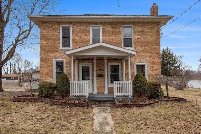 view of front of property featuring covered porch, brick siding, and a chimney